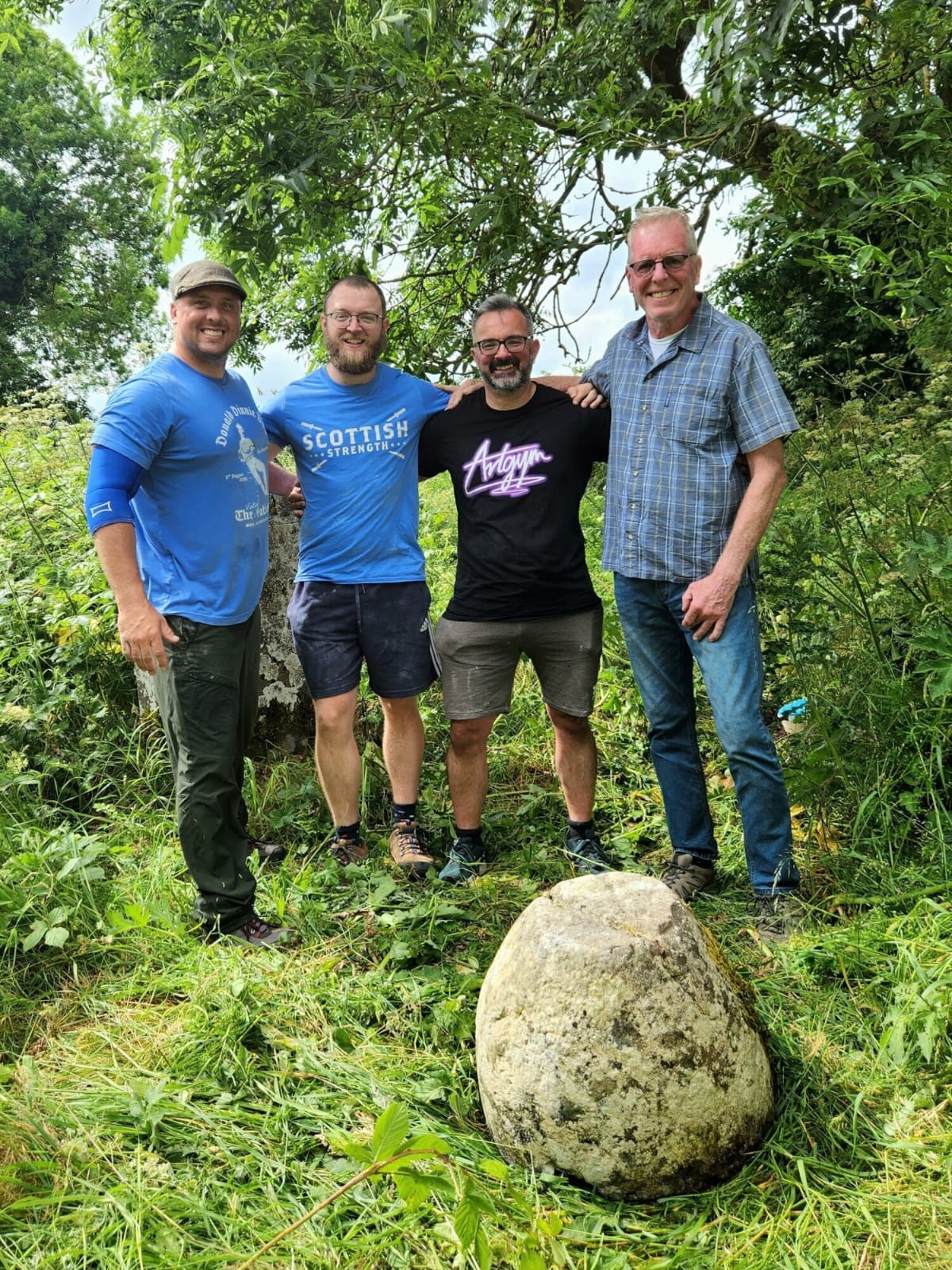 A group of men stand around an Irish lifting stone.