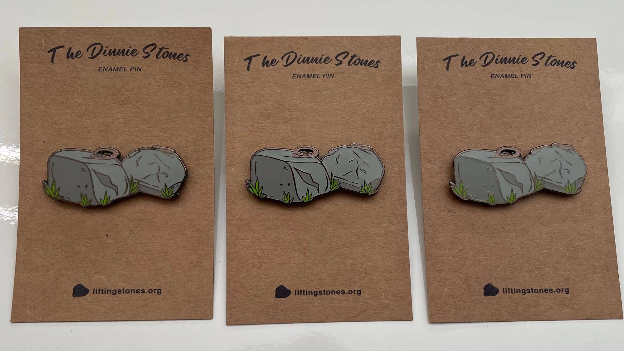 Three enamel pins attached to their backing cards on display.
