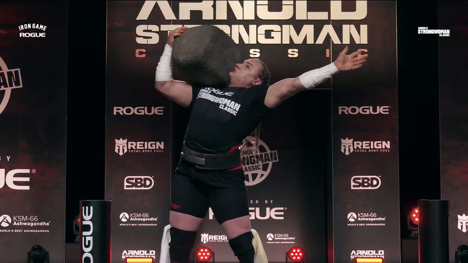 A screenshot from the Arnold Strongwoman Classic livestream. Olga Liashchuk stands with the Jeck Stone on her shoulder.