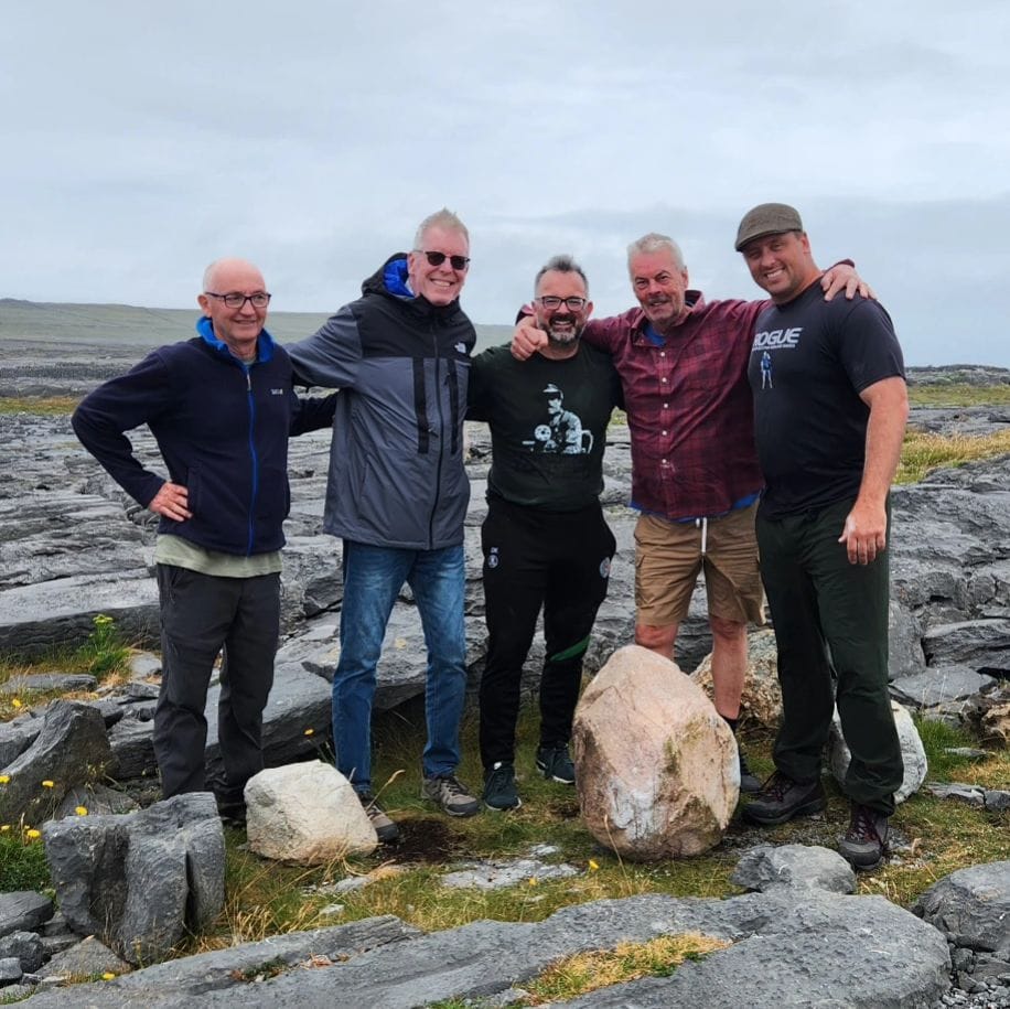 A group of five men pose for a photo next to the stone of Inishmore.