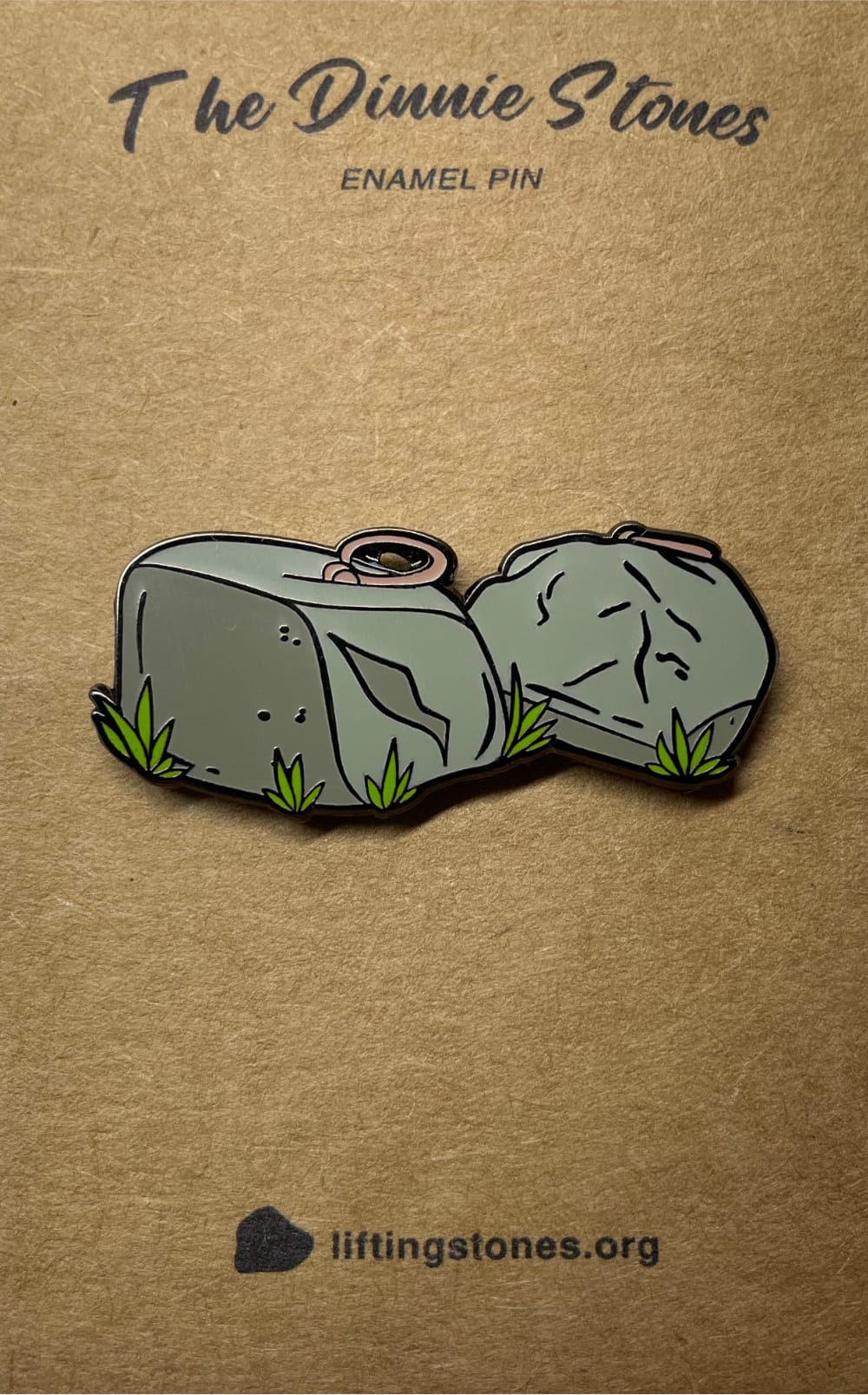 A picture of a Dinnie Stones enamel pin on a backing card.