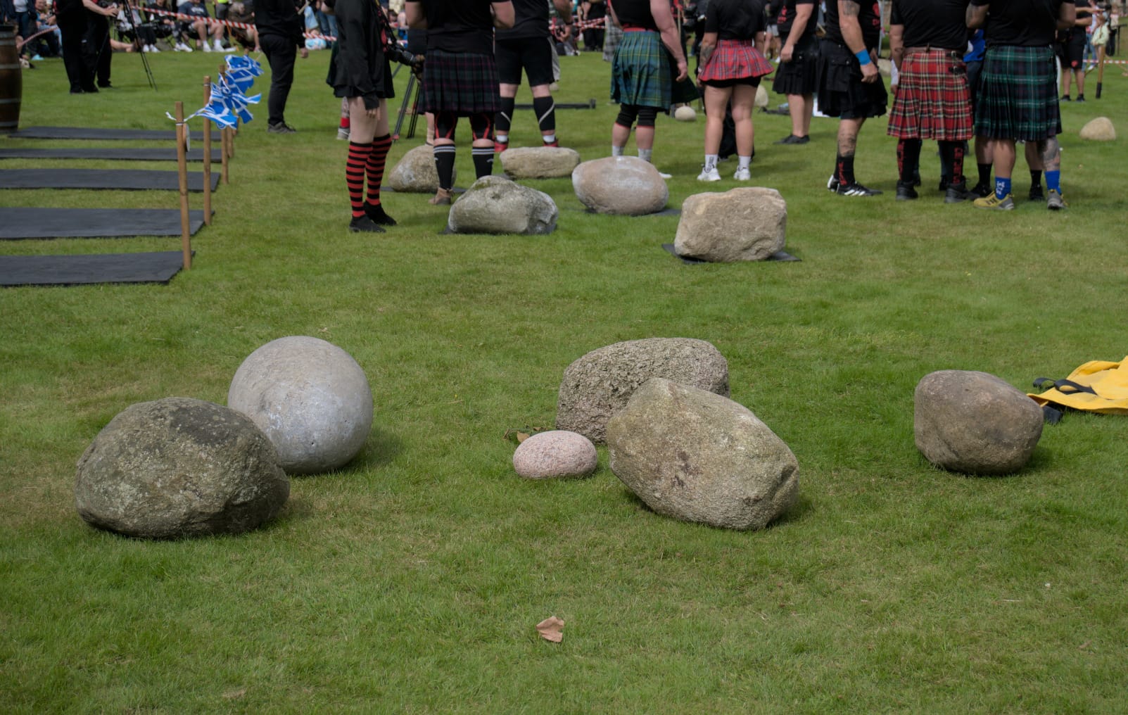 A set of 6 stones sit on grass in the foreground. A set of 5 stones sit on rubber mats in the background.