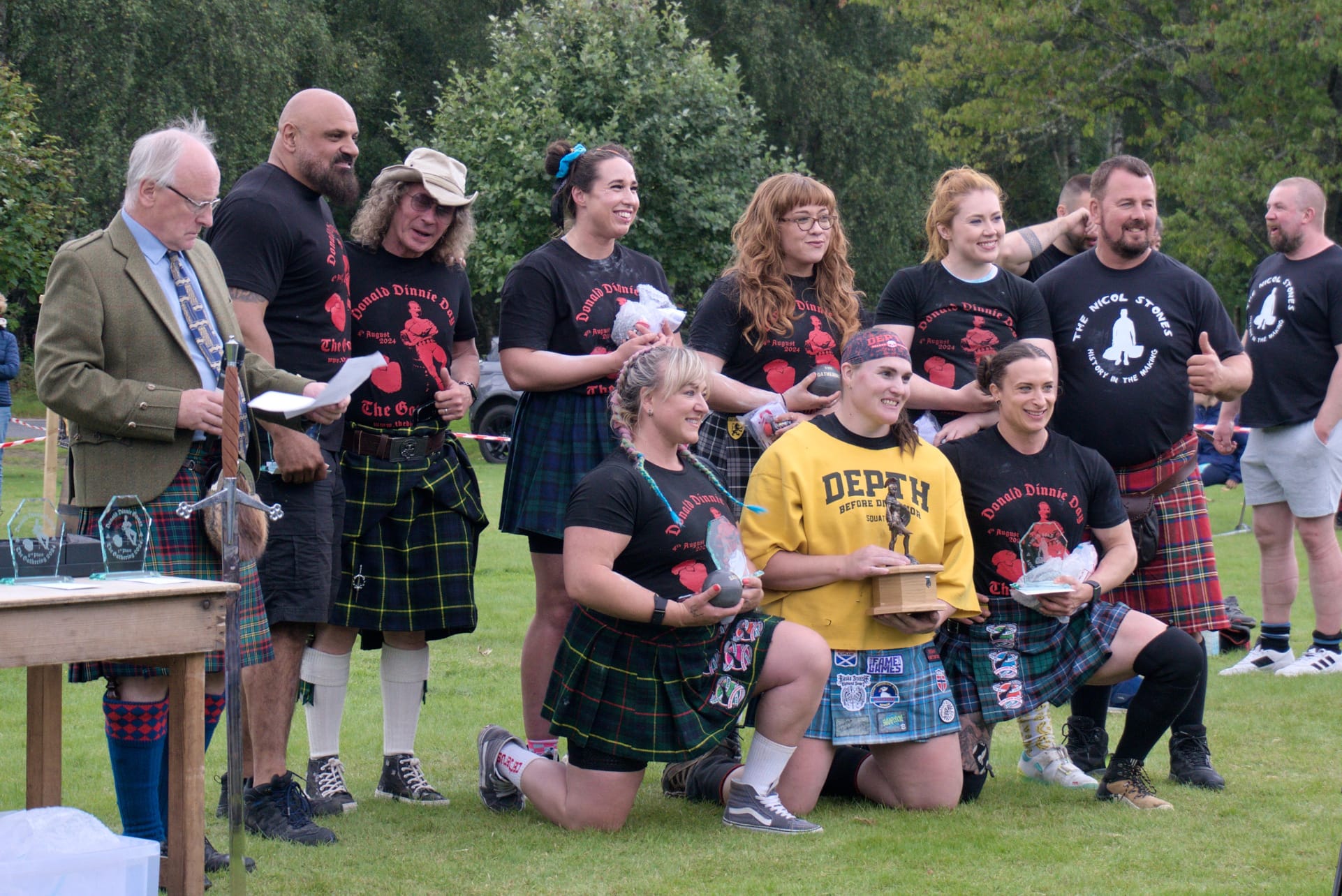 A group of athletes holding their awards get their photo taken.