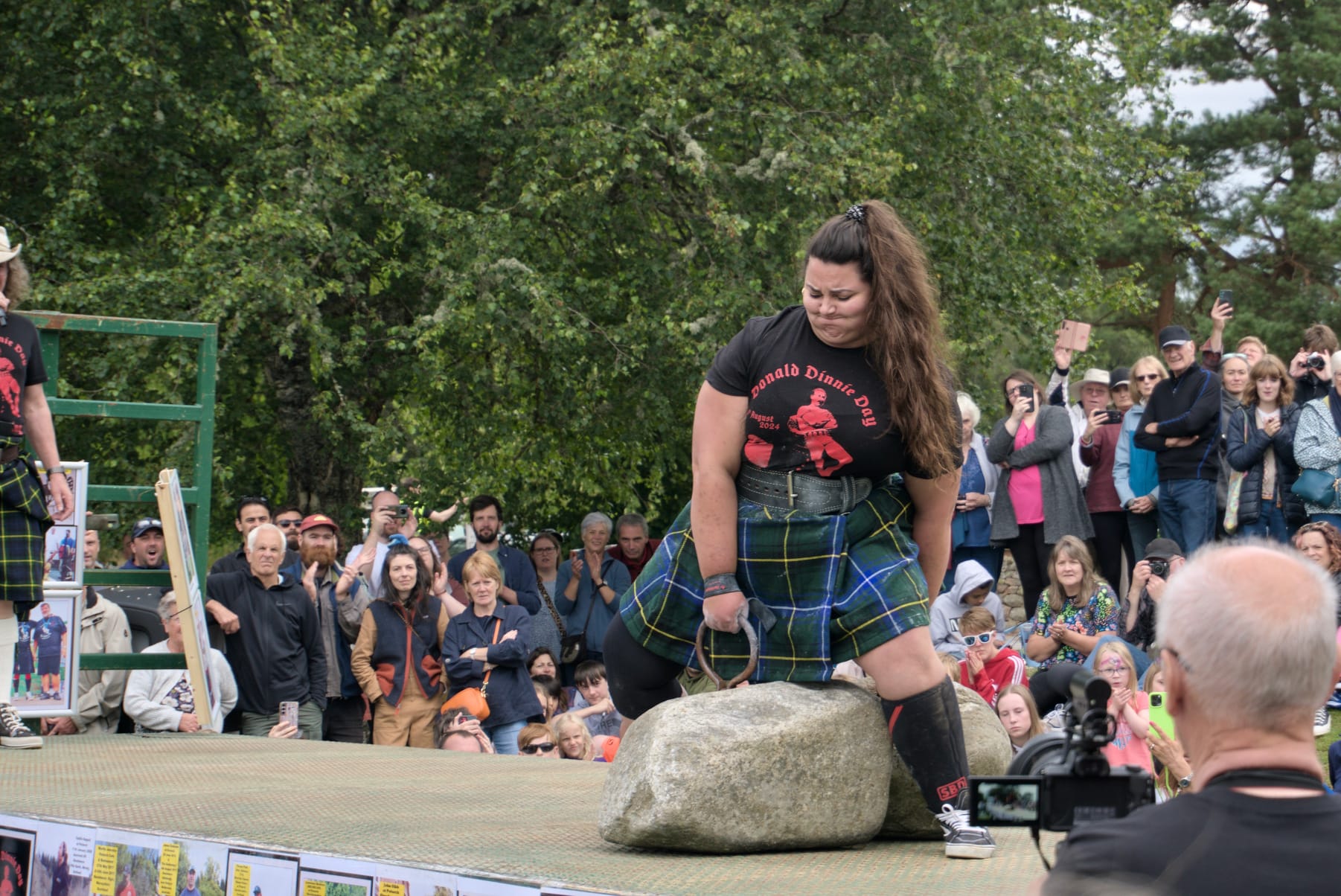 A woman strains while attempting to lift the Dinnie Stones.