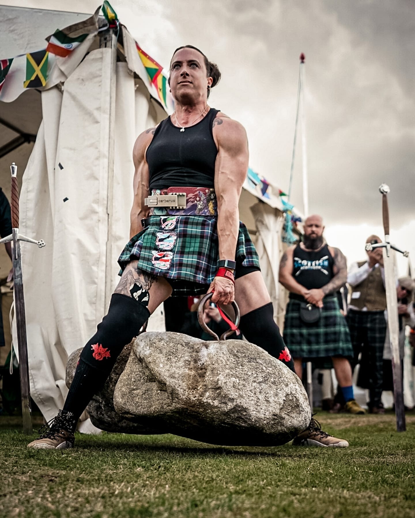 A woman stands tall with the Dinnie Stones between her legs. The stones are off the ground.