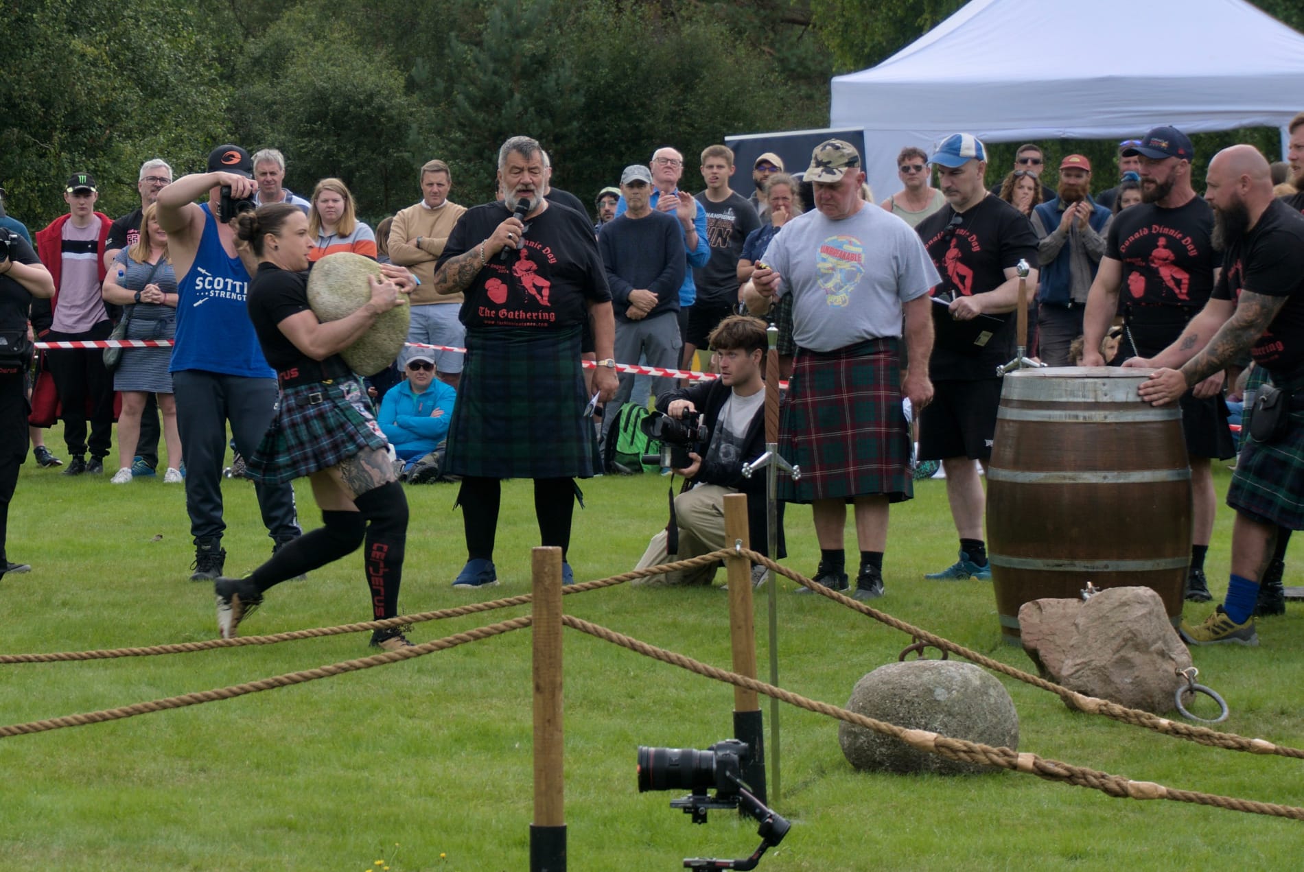 A woman holds a stone to her chest while running towards a barrel.