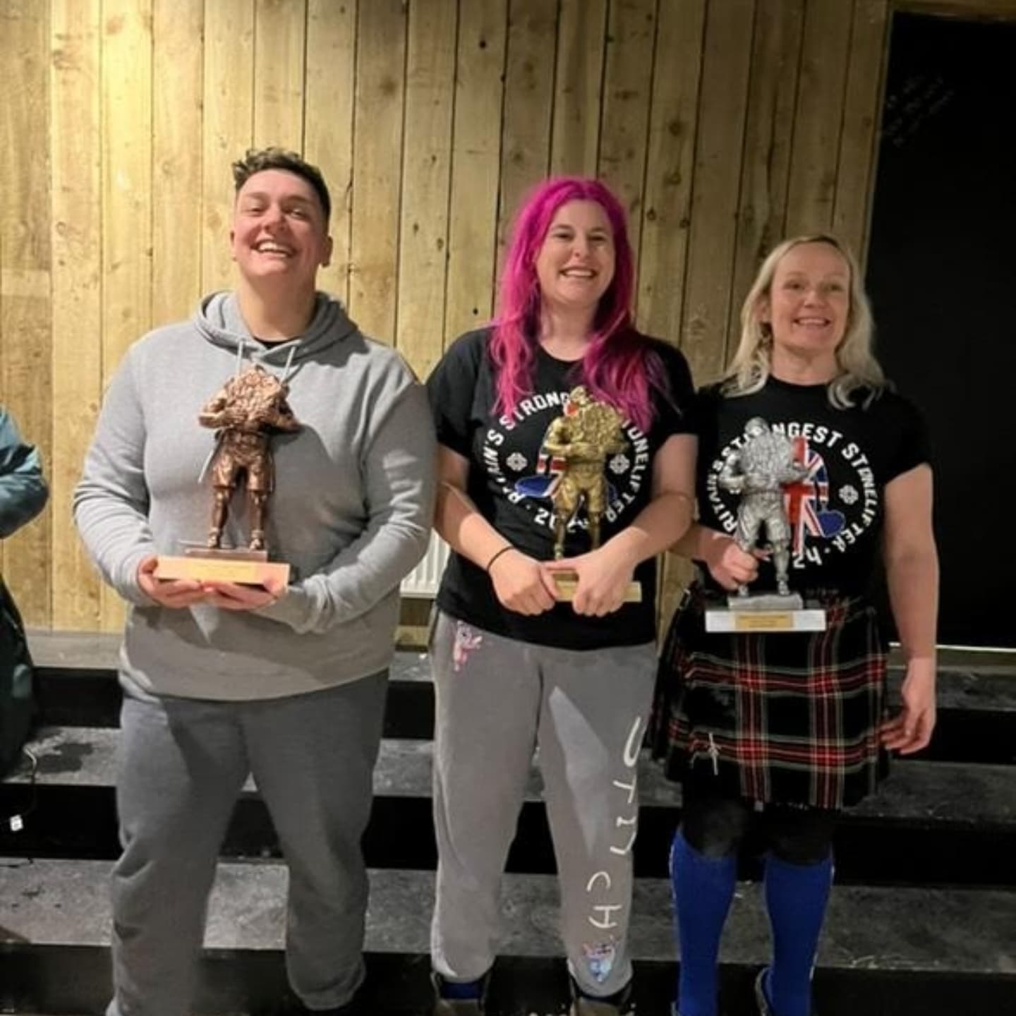 Three women pose for a photo with their podium trophies.