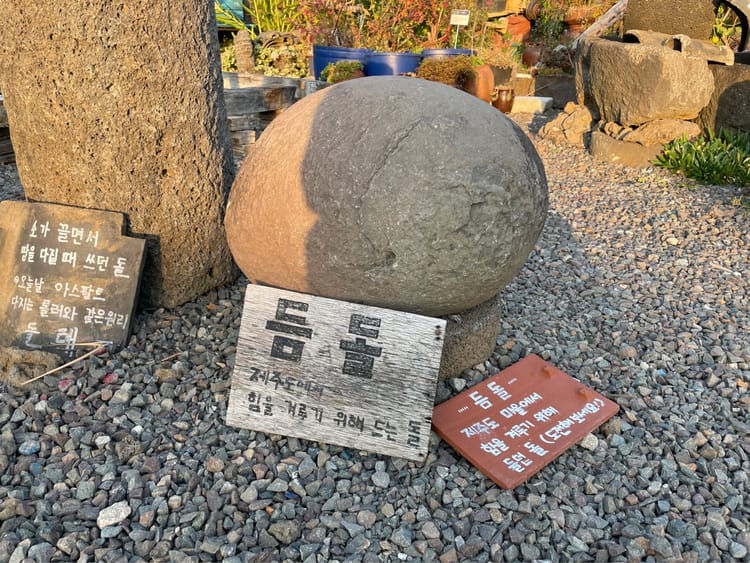 A stone sits on a small podium a few inches from the floor. There is a sign in Korean.