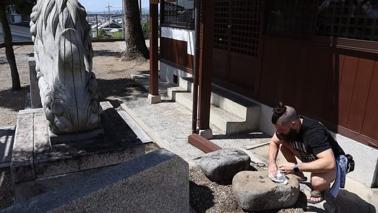 David 'Tamotsu' Dunlap cleans the dirt from a stone.