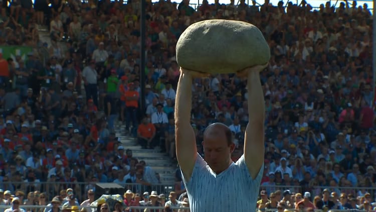 A man holds the Unspunnen stone above his head.