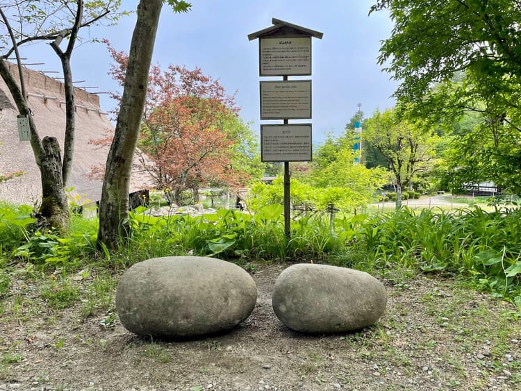 A pair of smooth, round stones sit side-by-side. A larger one sits on the left, a smaller one on the right.